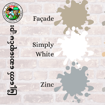 Paint splotches on brick façade with city paint program title in Burmese