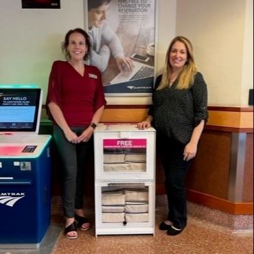 Two women standing next to old newspaper box made into a Narcan dispenser