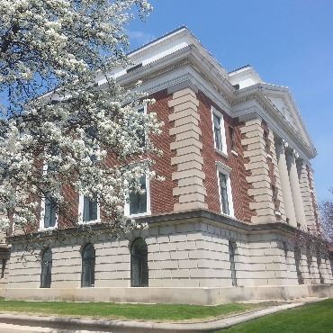 Historic Battle Creek City Hall with flowering tree next to it.
